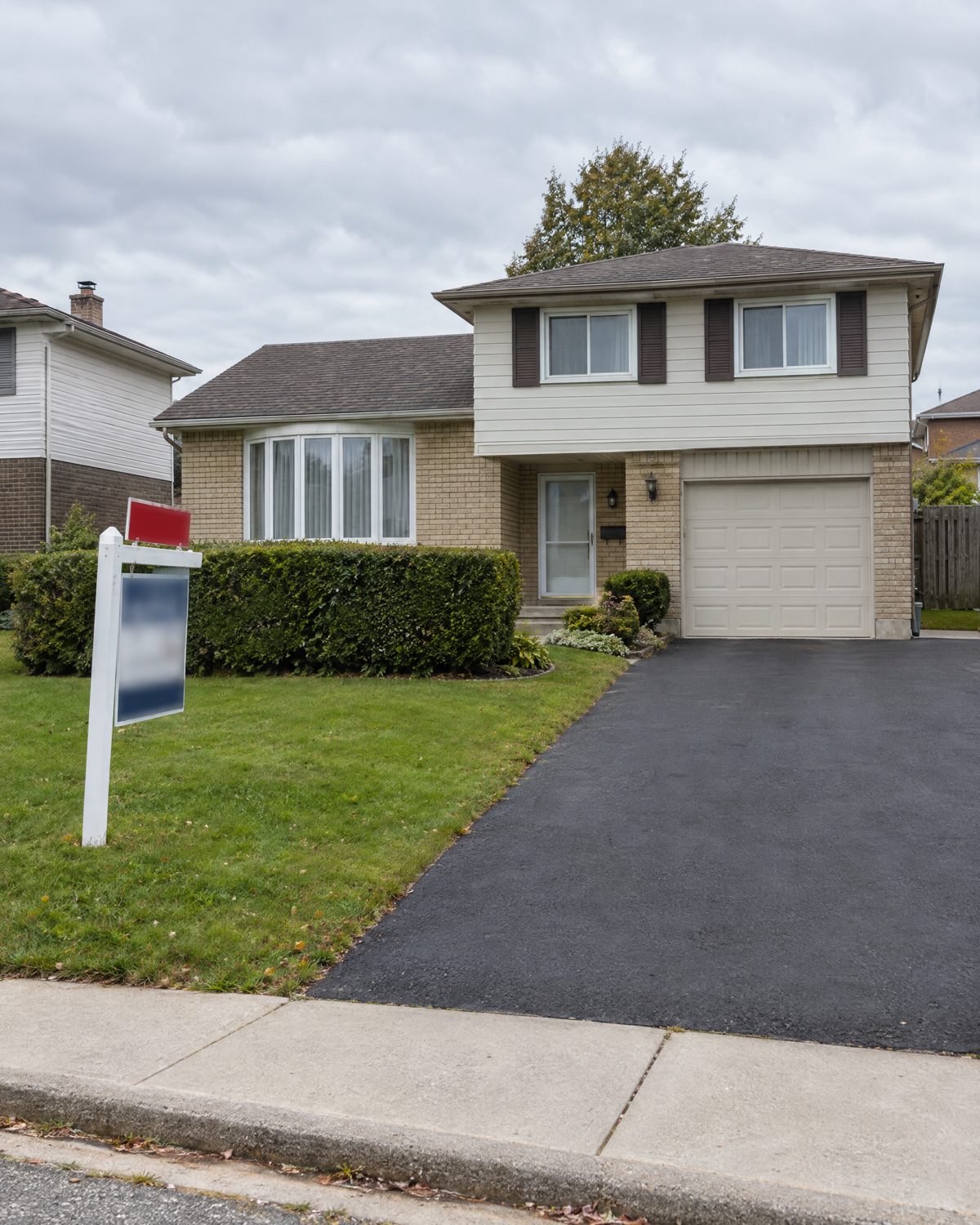 1970s side-split detached house in Bramalea, Brampton, with a new asphalt driveway and a sold sign by the hedge