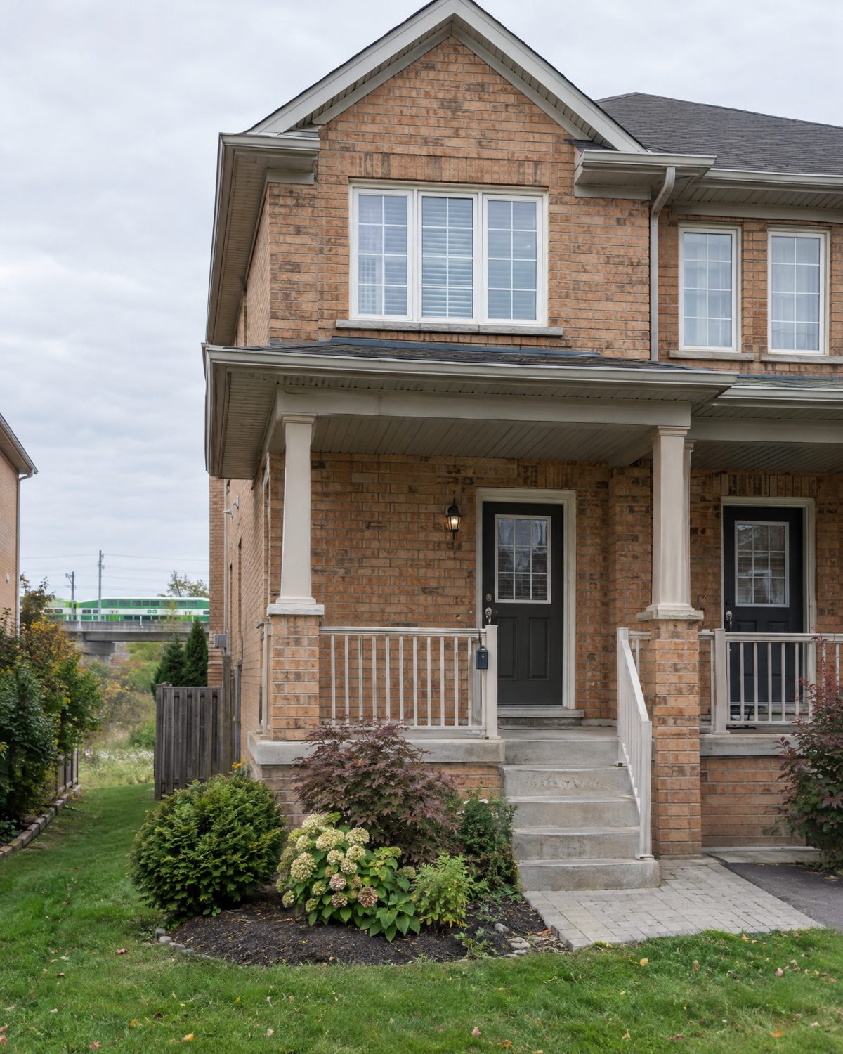 Front porch and brick facade of a 2000s semi-detached house in Maple, Vaughan, with a lockbox on the railing