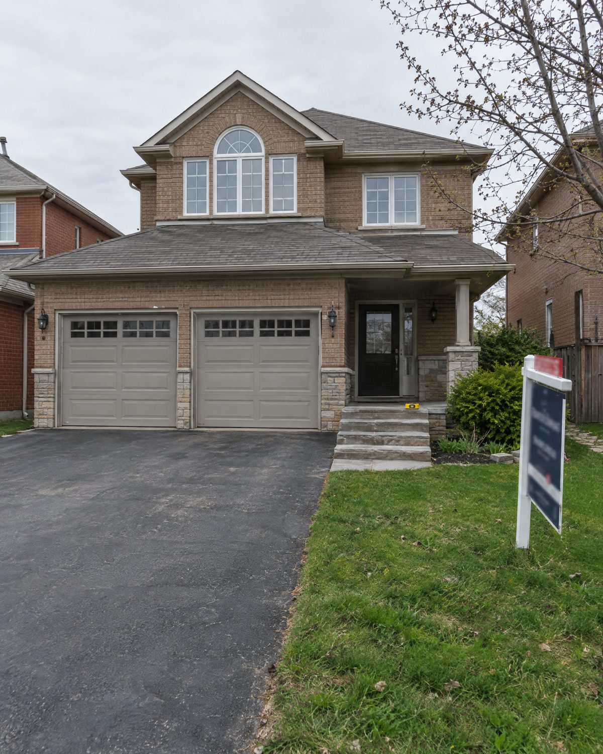 Double garage and stone front steps of a 1990s detached house in Springdale, Brampton, with a measuring tape on the step