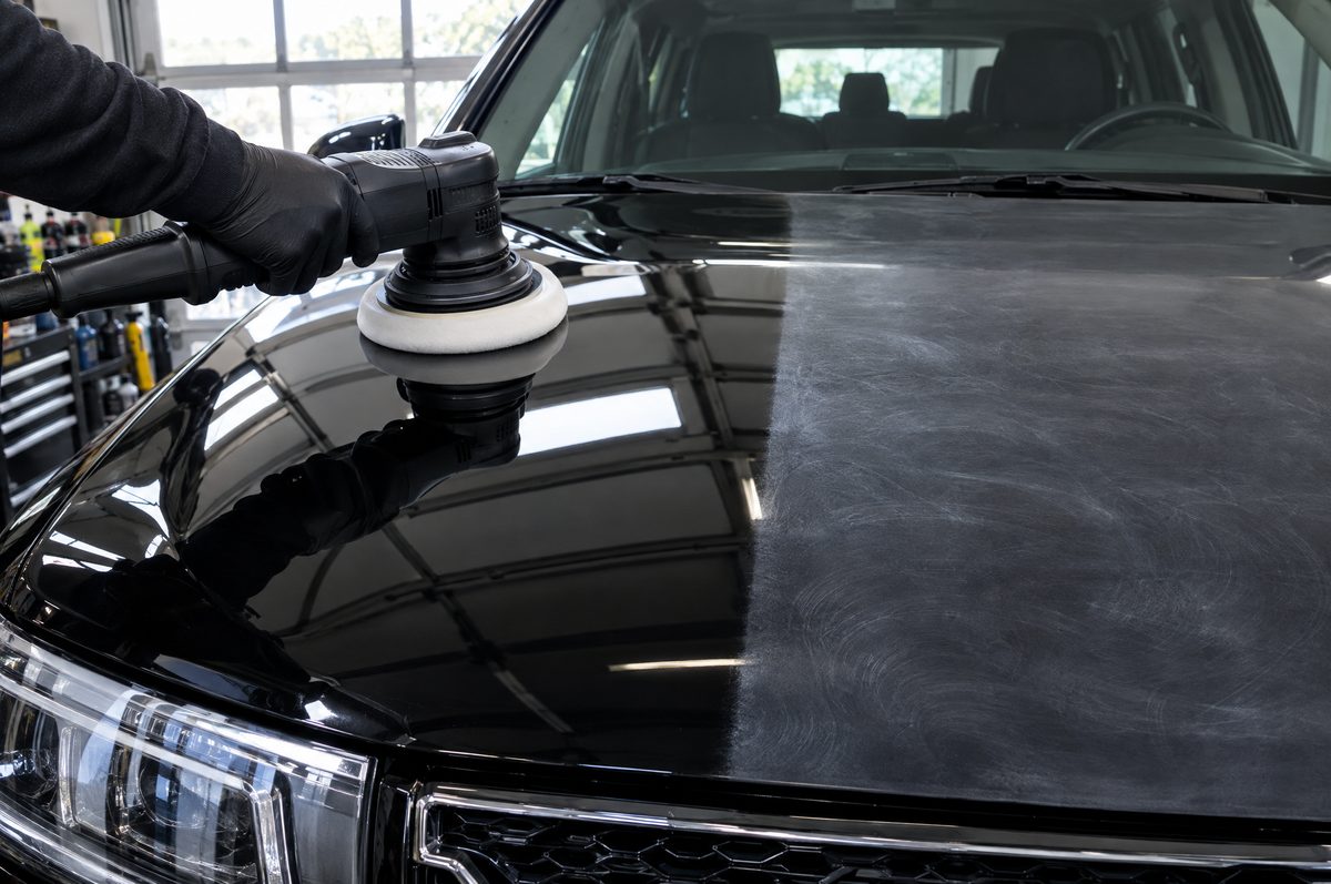 A machine polisher on a black hood, half polished