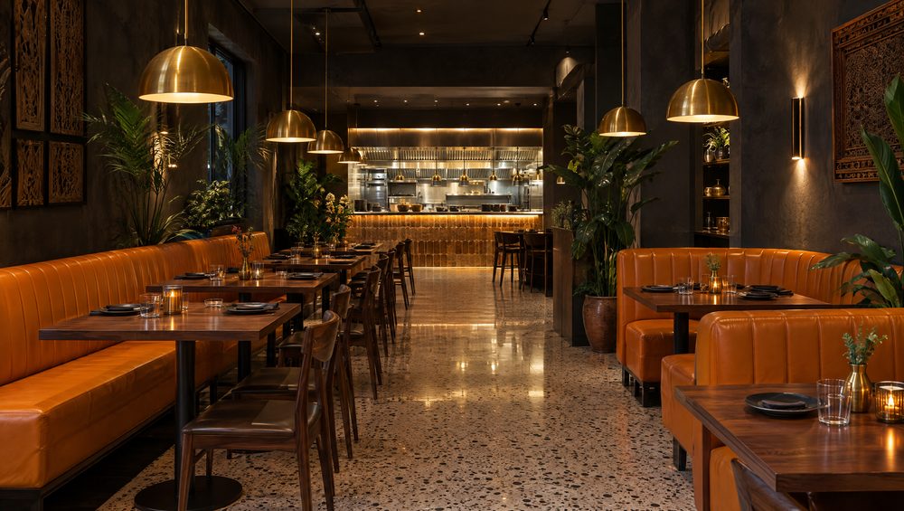 The dining room: marigold banquettes, brass pendants, terrazzo floor